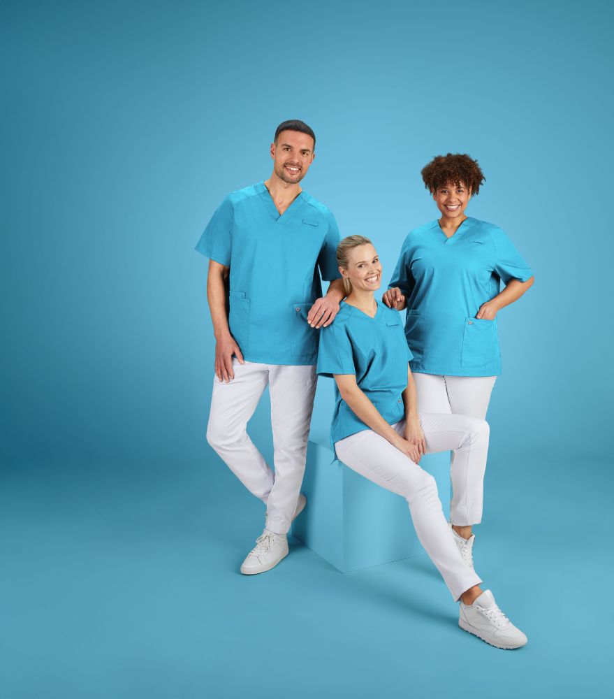 2 Pflegerinnen und 1 Pfleger in hellblau-weißer Pflegekleidung sitzen auf dem Boden.